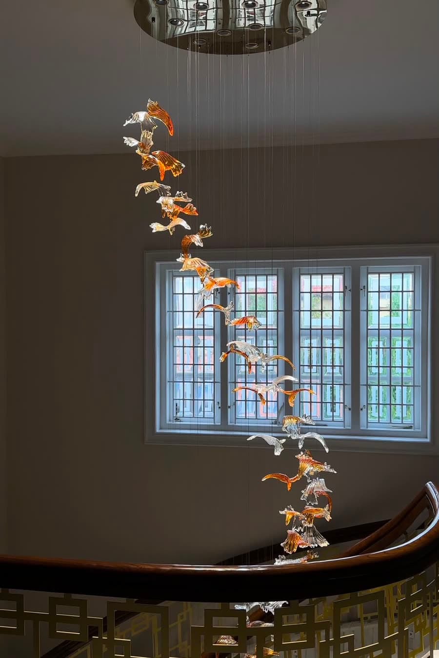 A glass cascade falling past a tall stairwell window