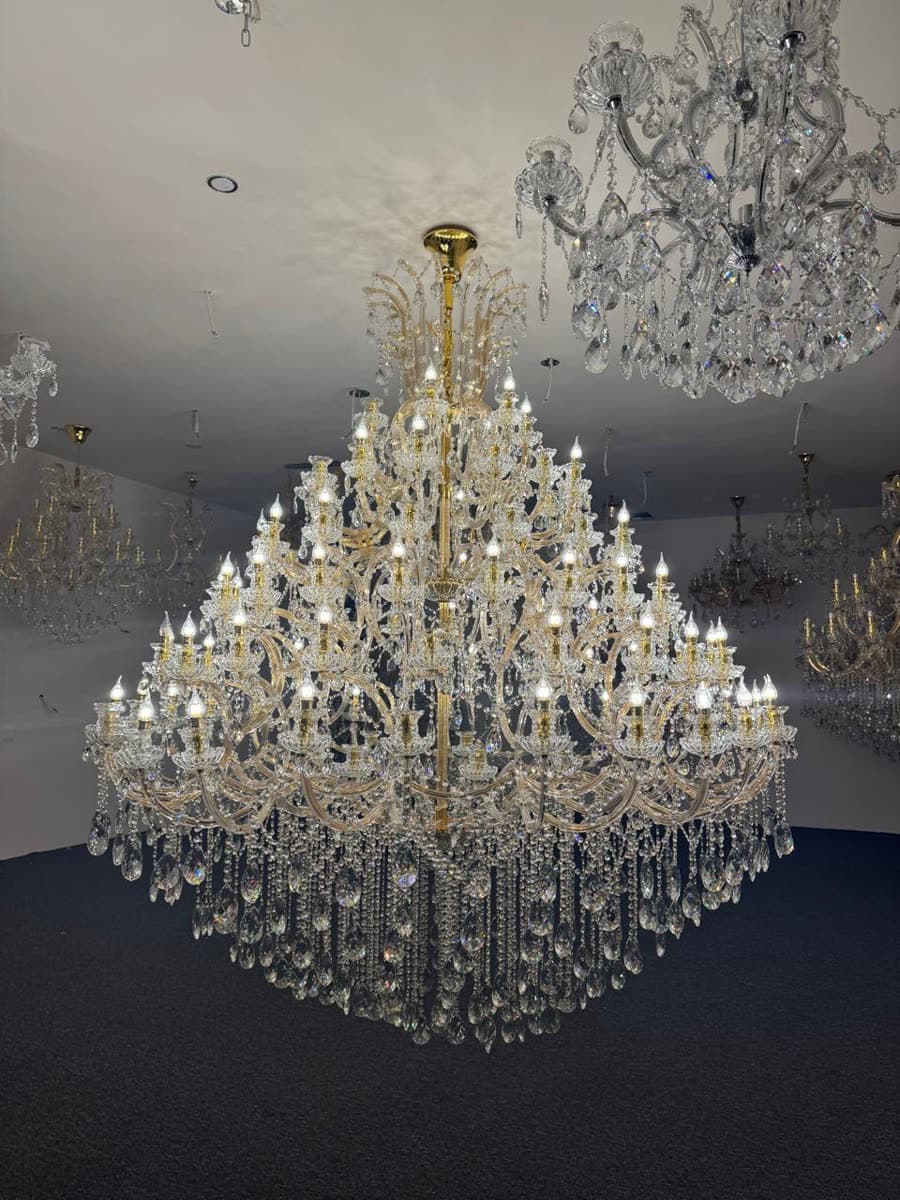 A large multi-tier crystal chandelier lit on a showroom floor